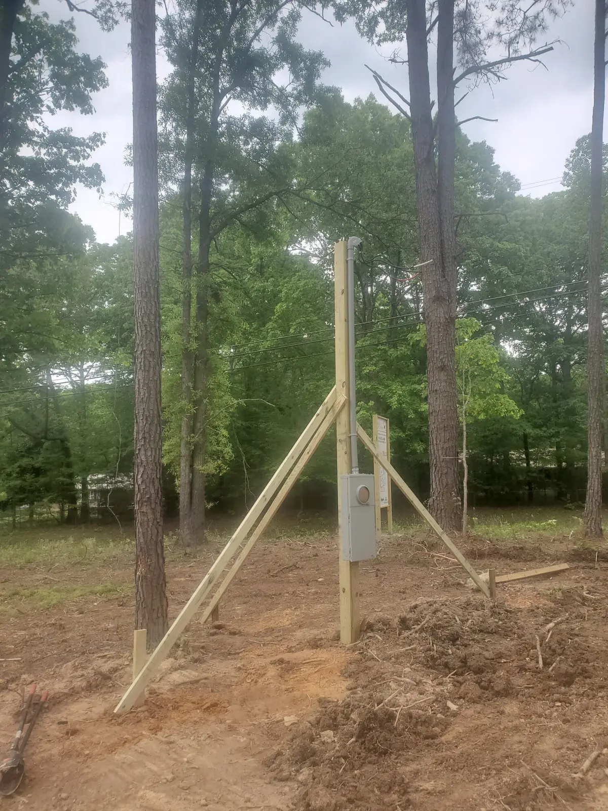 Temporary electrical service pole installed at a wooded construction site