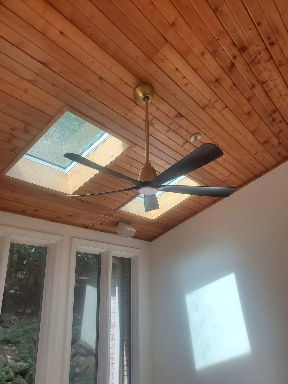 Bahama Electric’s custom ceiling fan installation in a light-filled room with a wood ceiling