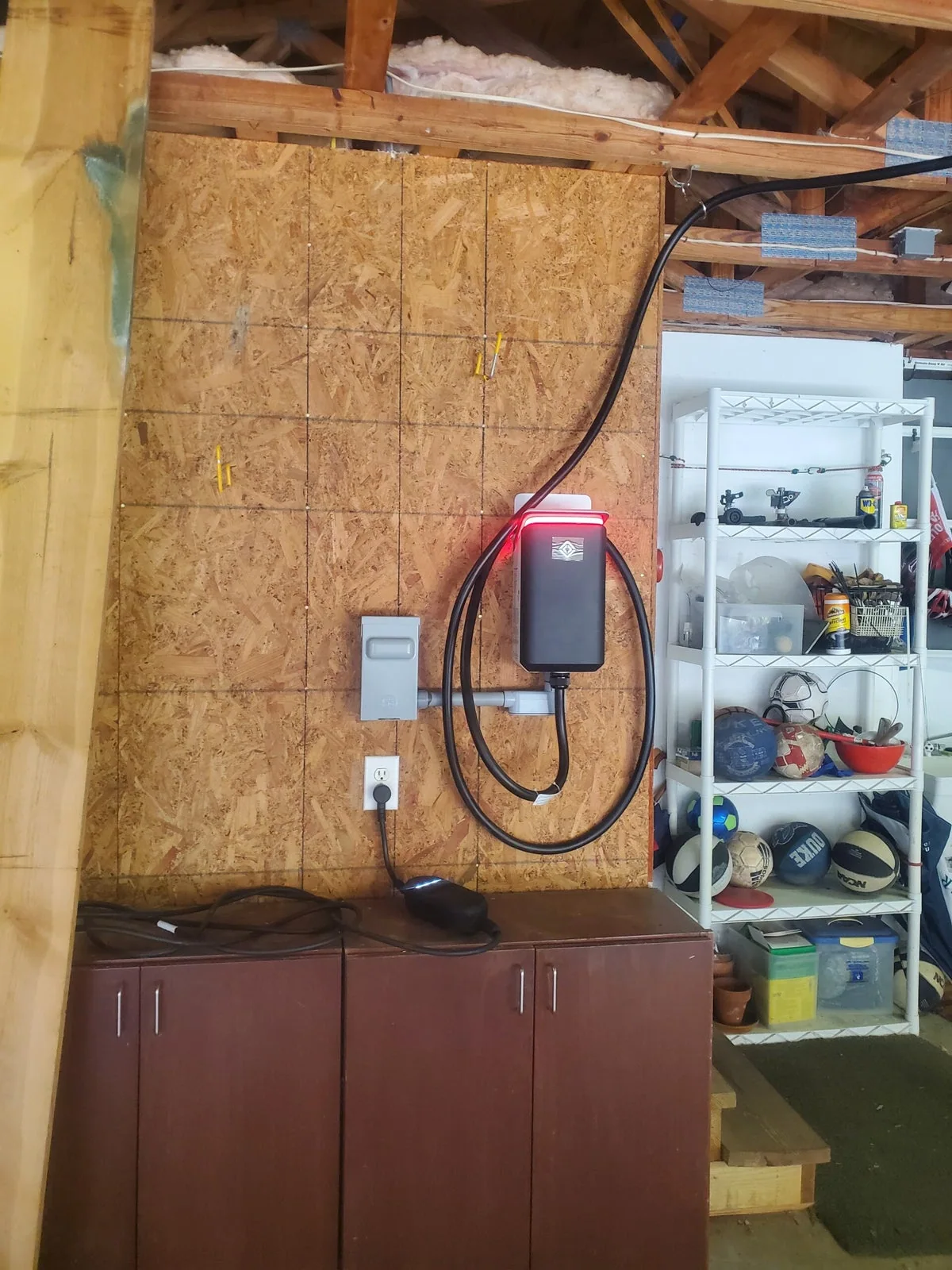 EV charger and neatly looped charging cable mounted on a garage wall