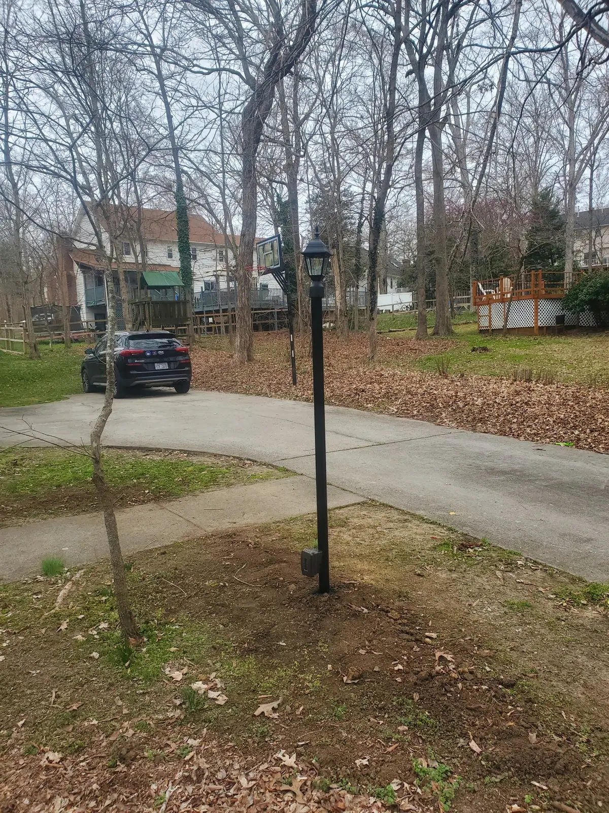 Black outdoor post lantern beside a residential driveway